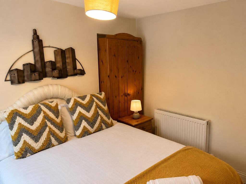 a bedroom with a bed with yellow and brown pillows at 54 - Room 2 - Smart Tv in Swansea