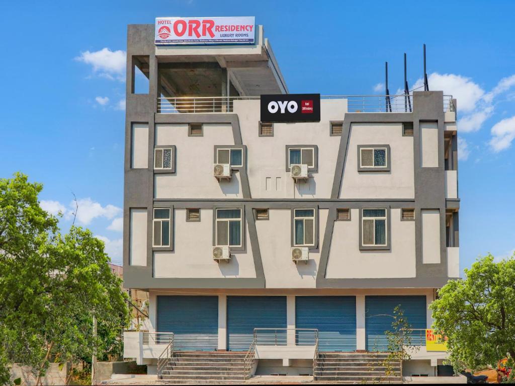 a tall white building with a sign on it at HOTEL O ORR RESIDENCY in Hyderabad