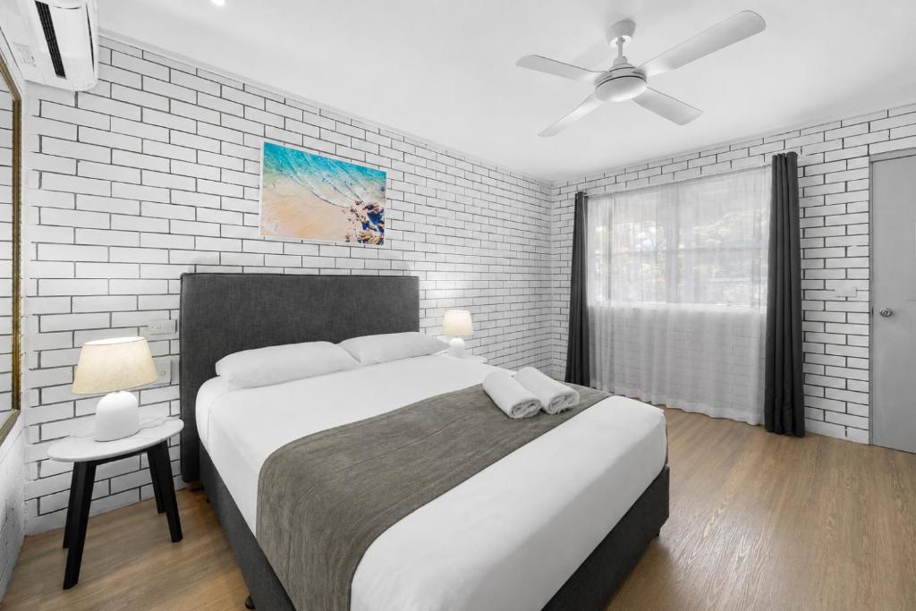 a bedroom with a large bed with a ceiling fan at Pacific Paradise Airport Motel in Pacific Paradise 