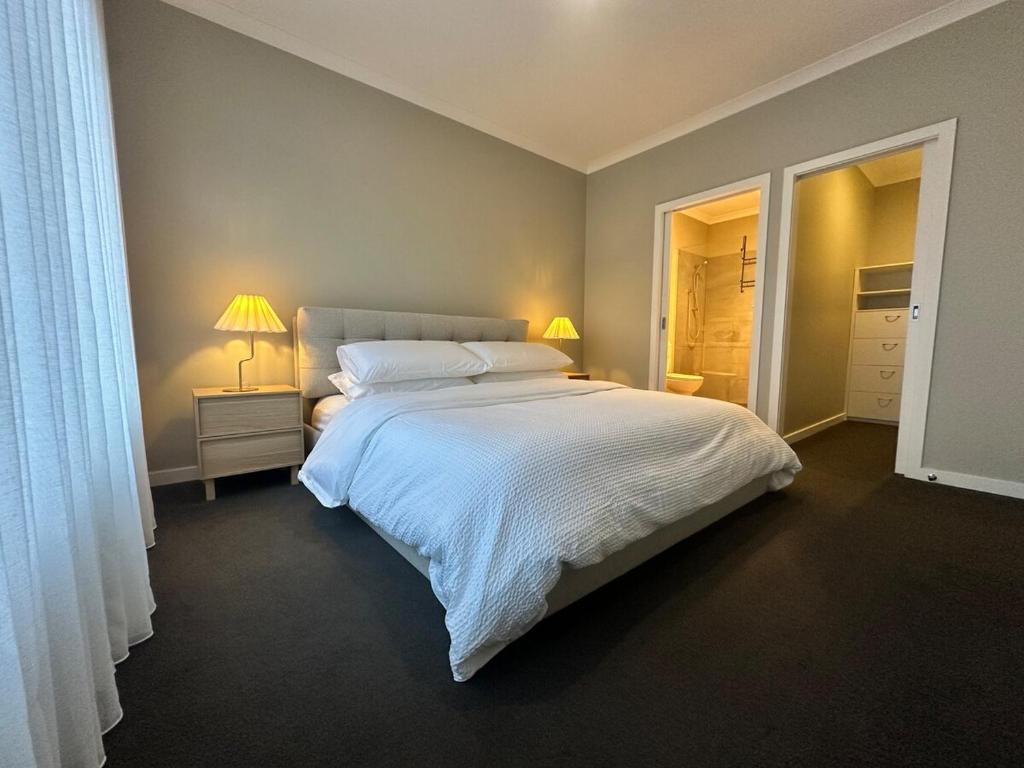 a bedroom with a large white bed and two lamps at Central 3BR Home in Mansfield