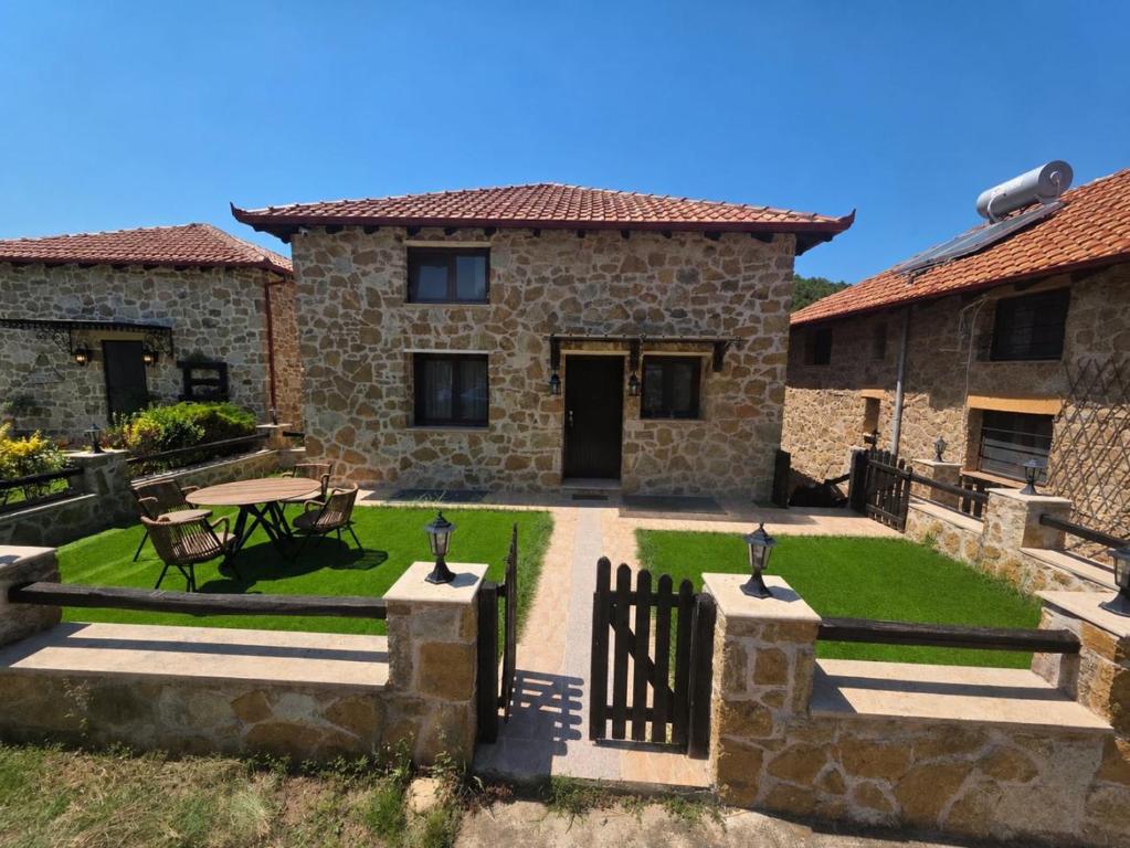 a stone house with a patio and a table at Lithos Villas Komitsa in Metókhion Koumítsas