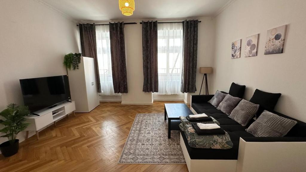 a living room with a black couch and a tv at Holstentor Apartment in Lübeck