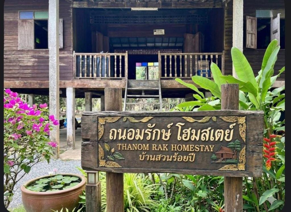 a sign in front of a house with a building at Thanomrak homestay in Ban Pha Saeng Lang