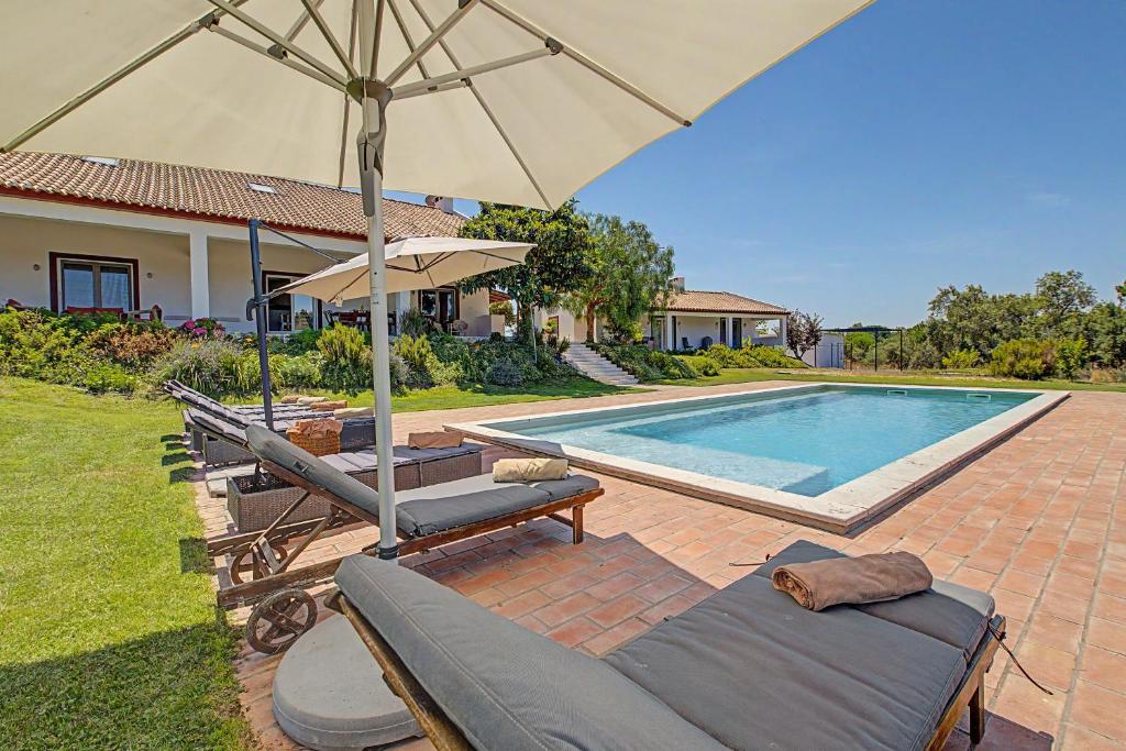 a pool with two lounge chairs and an umbrella at Monte Do Poço Country House in Erra