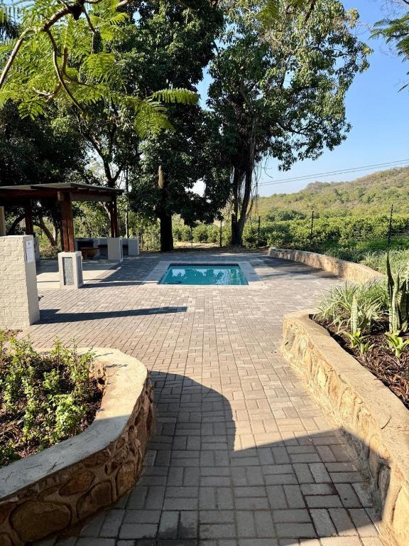 a swimming pool in the middle of a patio with trees at Die Boord Guesthouse in Crocodile Valley Estates