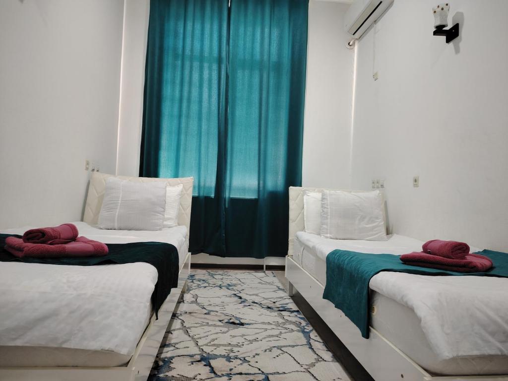 two beds in a room with a blue window at Chevrolet Hotel in Namangan