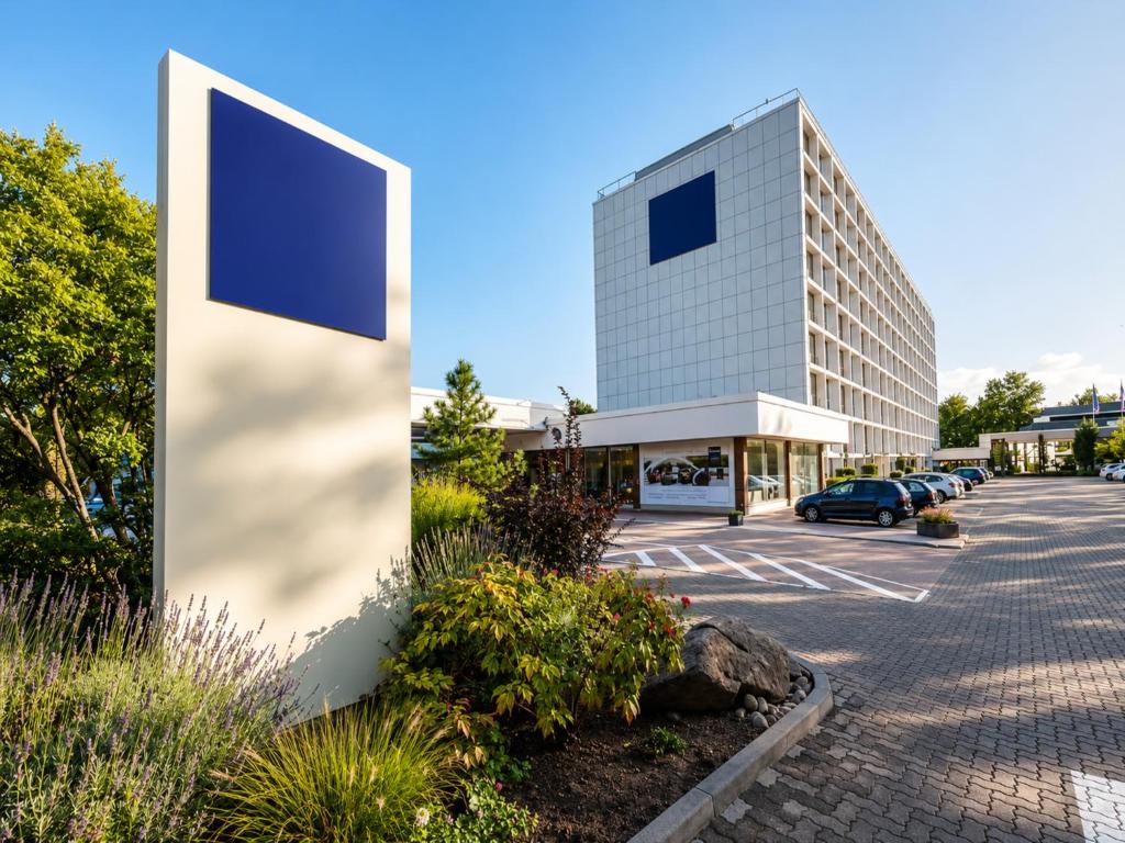 a large building with a parking lot in front of it at Main Taunus Zentrum Frankfurt Sulzbach by Sunday Hotels in Frankfurt
