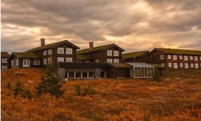 a large building with grass on top of a field at Nyt høsten på Toppen av Hafjell in Øyer