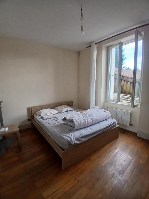 a bed in a bedroom with a large window at Riverside house in Issoudun