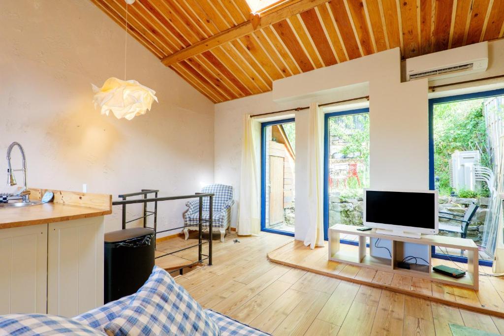a kitchen with a living room with a tv and a table at Maison de Charme - Écrin de Nature in Saint-Privat