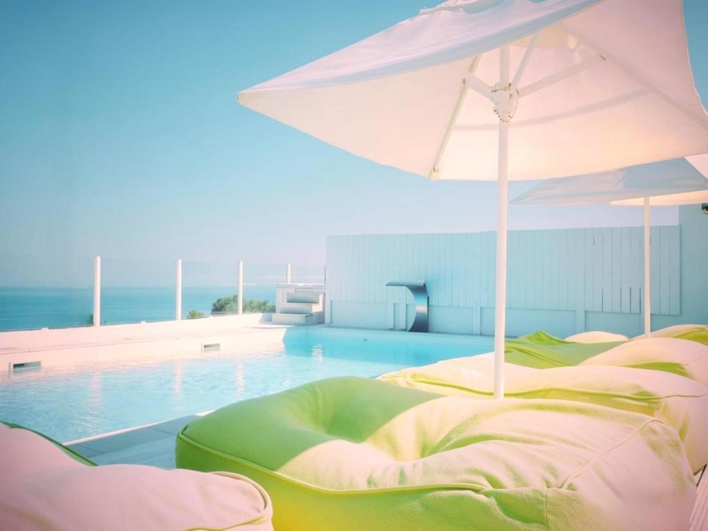 a pool with an umbrella next to a swimming pool at La Locanda Del Carrubo in Mattinata
