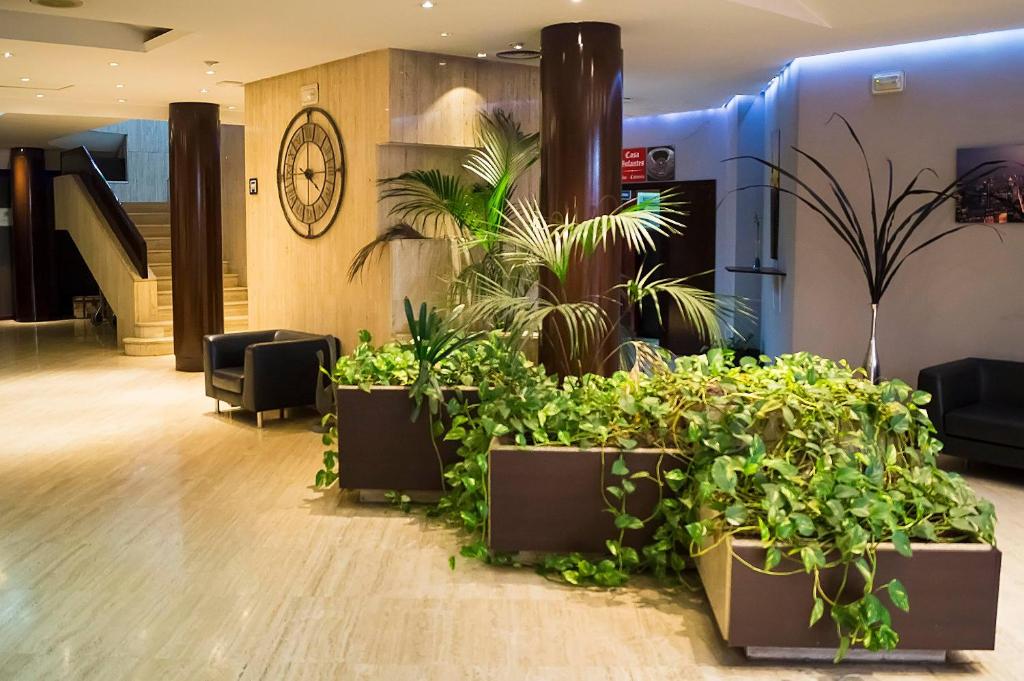 a lobby with several potted plants and a staircase at Hotel Puertollano in Puertollano