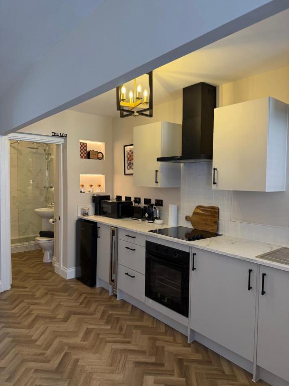 a kitchen with white cabinets and a wooden floor at Entire Flat in Lichfield City Centre in Lichfield