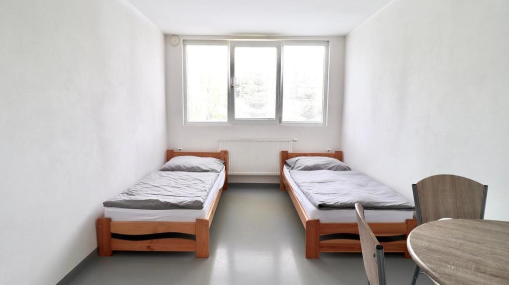a room with two beds and a table and a window at Ubytování U Hráze in Liberec