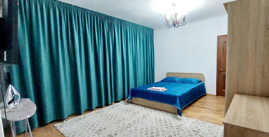 a bedroom with a bed and a green curtain at Яншина 6 in Qyzylorda