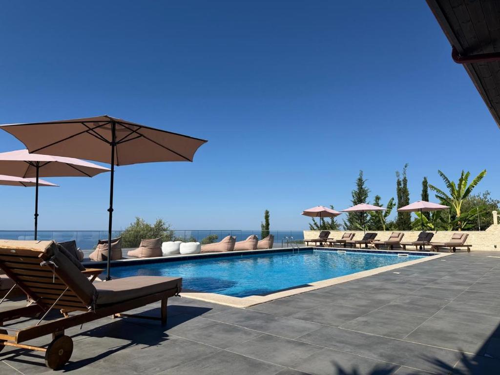 a swimming pool with chairs and umbrellas next to the ocean at Hotel Relax Dhermi in Dhërmi