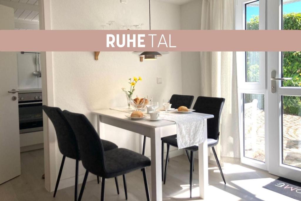 a white dining room table with black chairs and a kitchen at Ruhetal -Ferienwohnung mit Sonnenterasse in Glücksburg