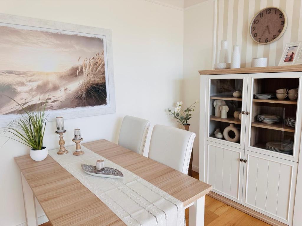 a dining room table with white chairs and a clock at Wellness-Oase-Nossen Kirchblick in Nossen
