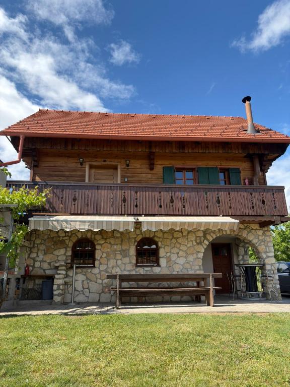 a house with a wooden roof and a bench in front at Cozy Winehouse - Remote Vineyard Escape in Podčetrtek