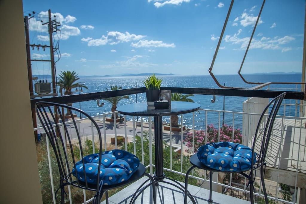 a balcony with a table and chairs and the ocean at Saronic View Studio in Agioi Theodoroi