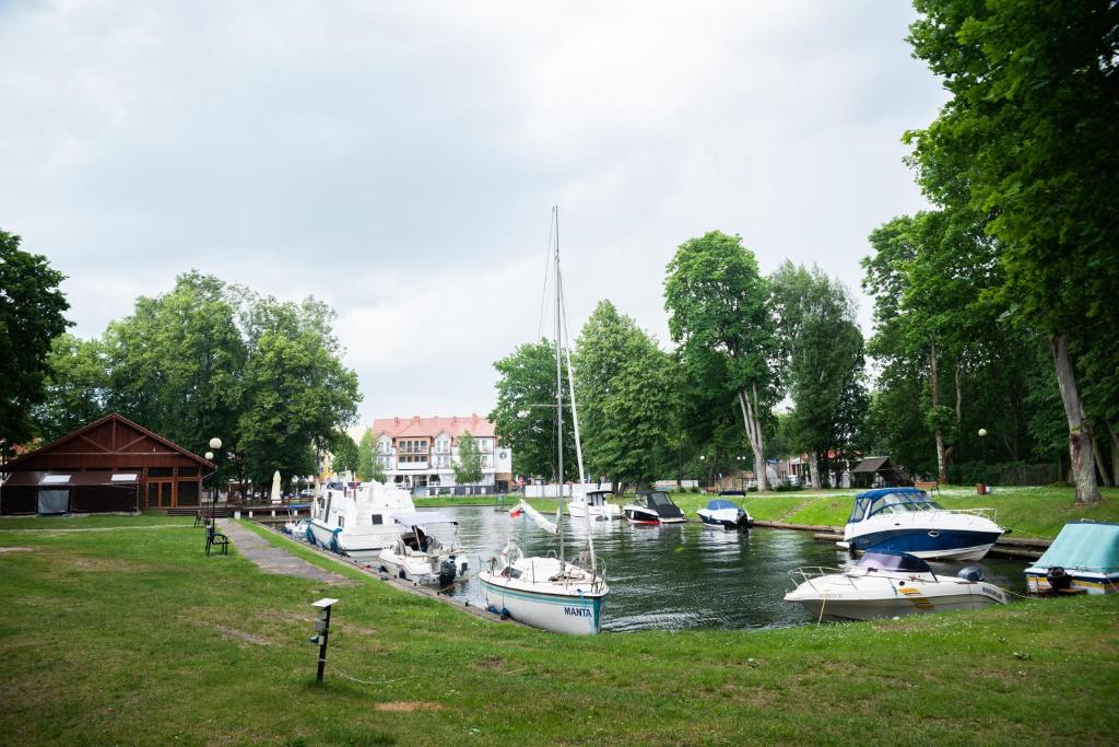 a group of boats are docked in a river at Camping ZAMEK C1 in Giżycko