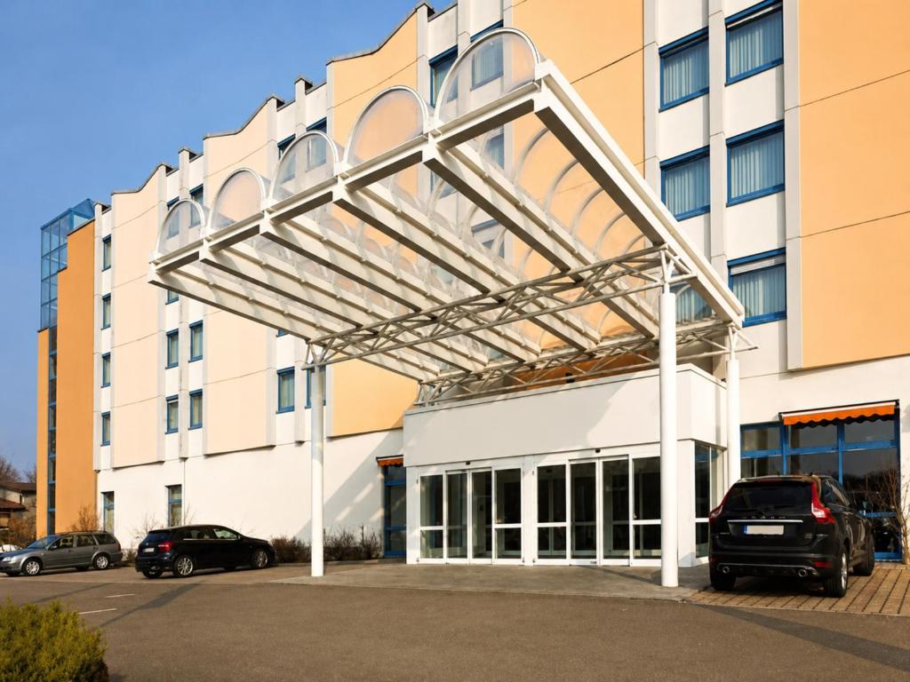 a large building with awning over a parking lot at Sunday Hotel Leipzig-Halle in Landsberg OT Peißen