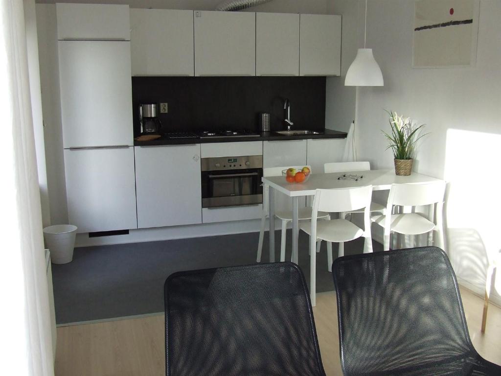 a kitchen with white cabinets and a table and chairs at De Viool in Buren