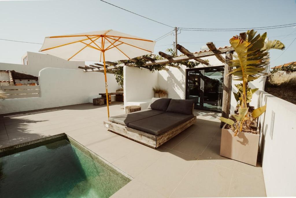 a patio with a couch and an umbrella and a pool at Suites Daldeia - Suite 1 in Azueira