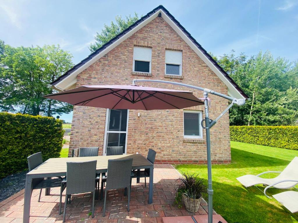 a table with an umbrella in front of a house at Ferienhaus Ella am See in Aurich