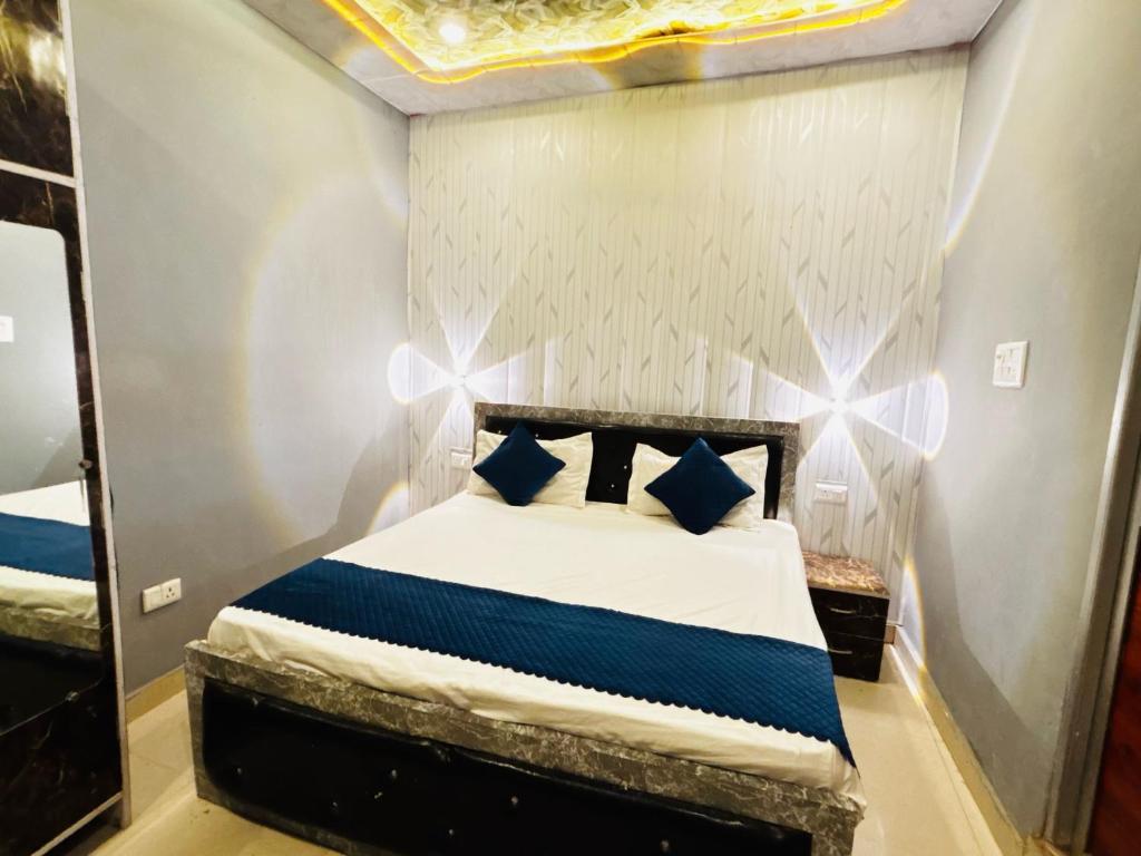 a bedroom with a bed with blue pillows and a mirror at Hotel O Suryavanshi Palace in Ayodhya