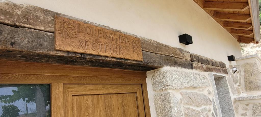 a building with a wooden sign above a door at A Bodega da Xesteira in Melón