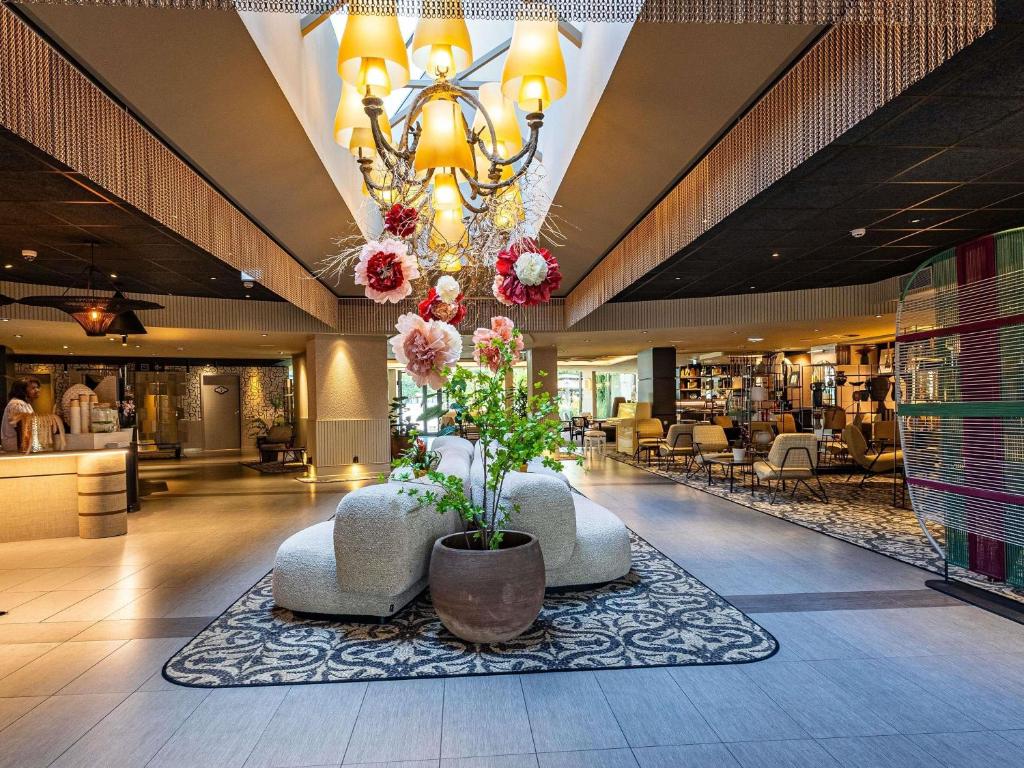 a lobby with a chandelier and flowers in a store at Novotel Marne La Vallée Collégien in Collégien