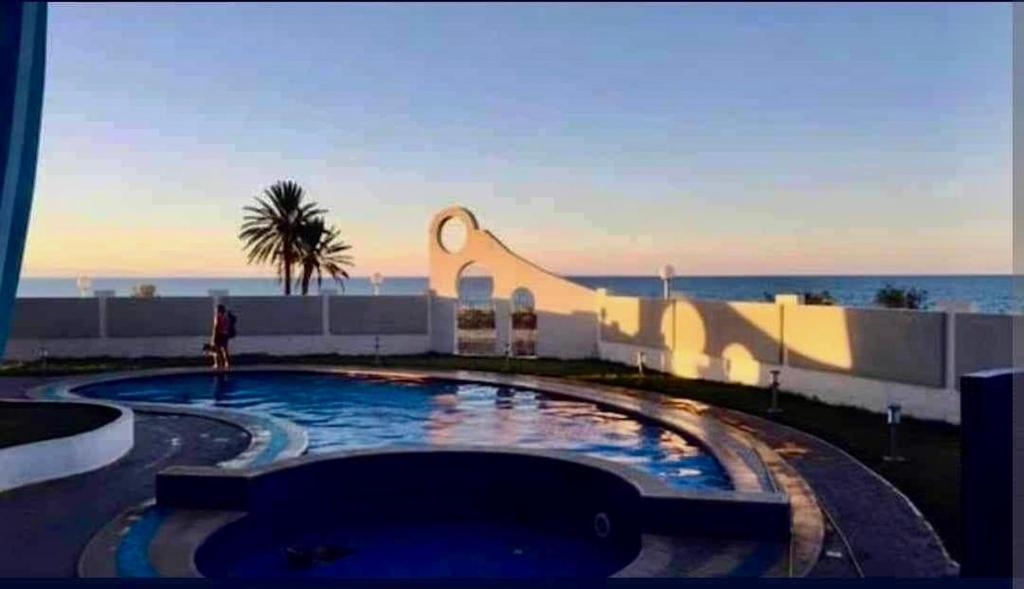 a person is standing next to a swimming pool at Kmayra Diamond in Harqalah