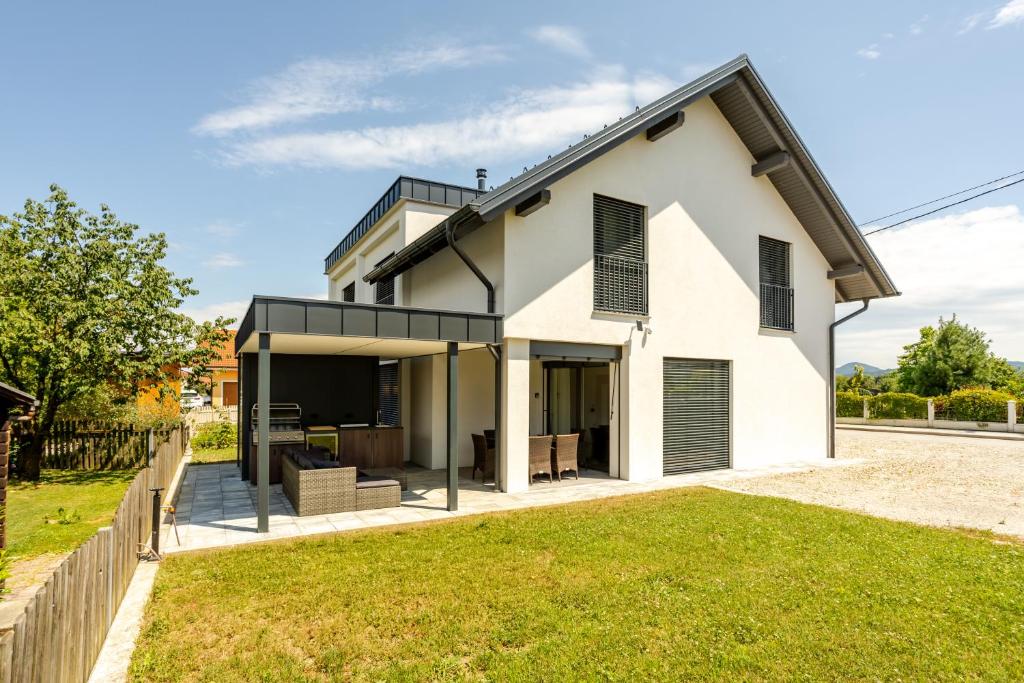 a white house with black windows and a yard at Hiša Urma in Celje