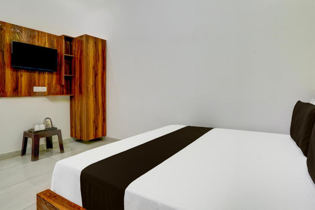 a bedroom with a bed and a tv on a wall at Hotel O Adinath Guest House in Bahādrābād