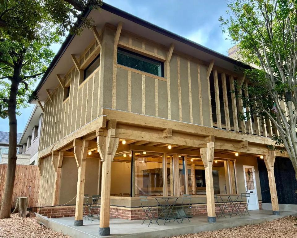 a house built on wooden posts with tables and chairs at 椿森コムナStay in Chiba