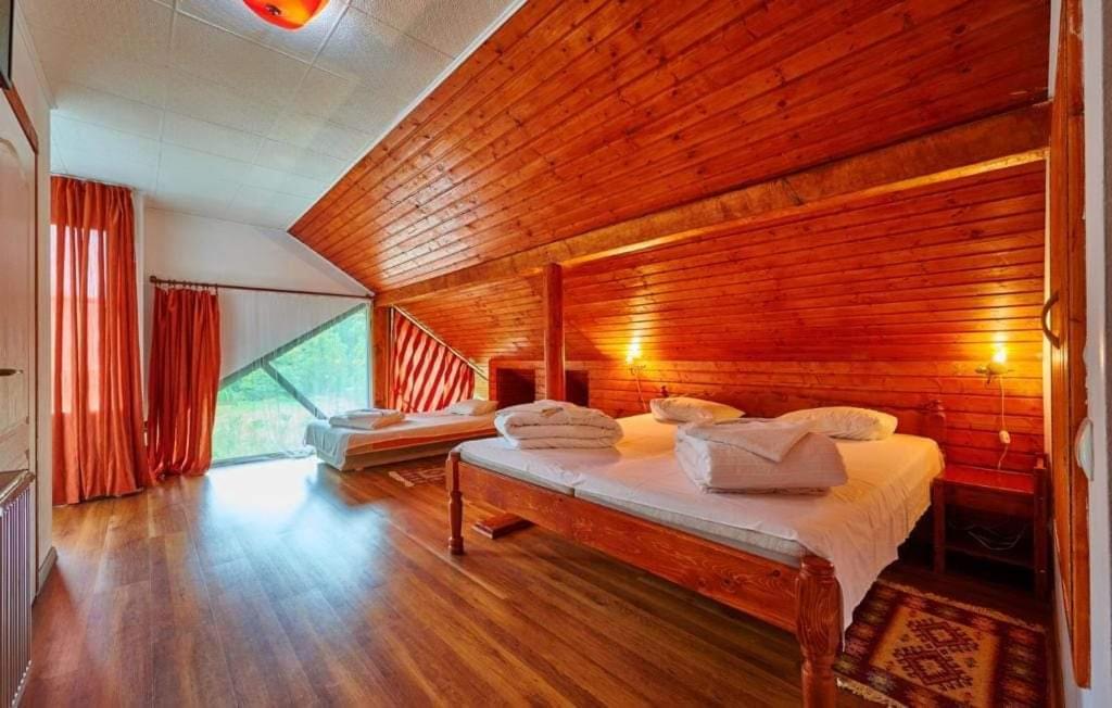 a bedroom with a bed in a wooden wall at La Moară la Făgădău in Tuşnad