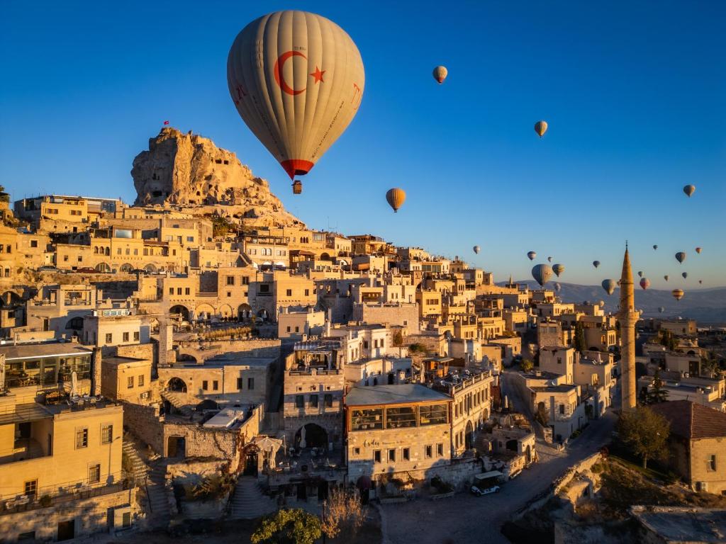 a group of hot air balloons flying over a city at Petra Inn Cappadocia Luxury in Uçhisar