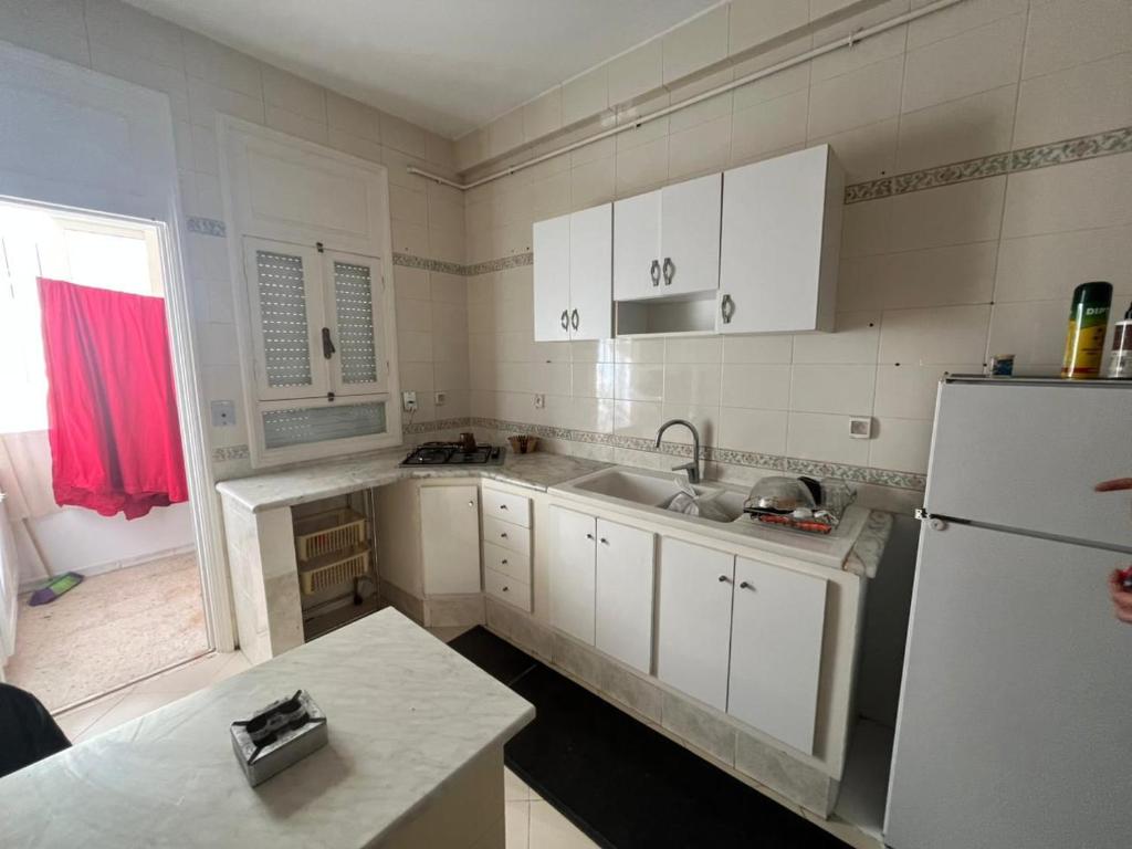 a kitchen with white cabinets and a sink and a refrigerator at Modern Flat , Master Suite , Ain Zaghouan in El Aouina Station