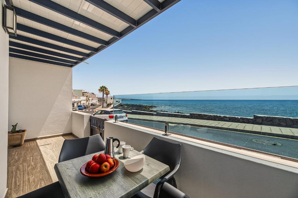 a table with a bowl of fruit on a balcony with the ocean at Callao Beach 1 in Arrieta