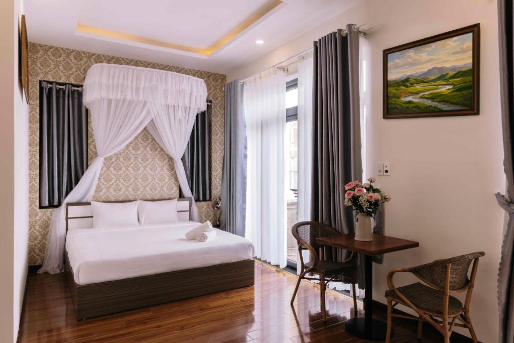 a bedroom with a white bed and a table and a desk at Hoanglee Villa in Da Thanh