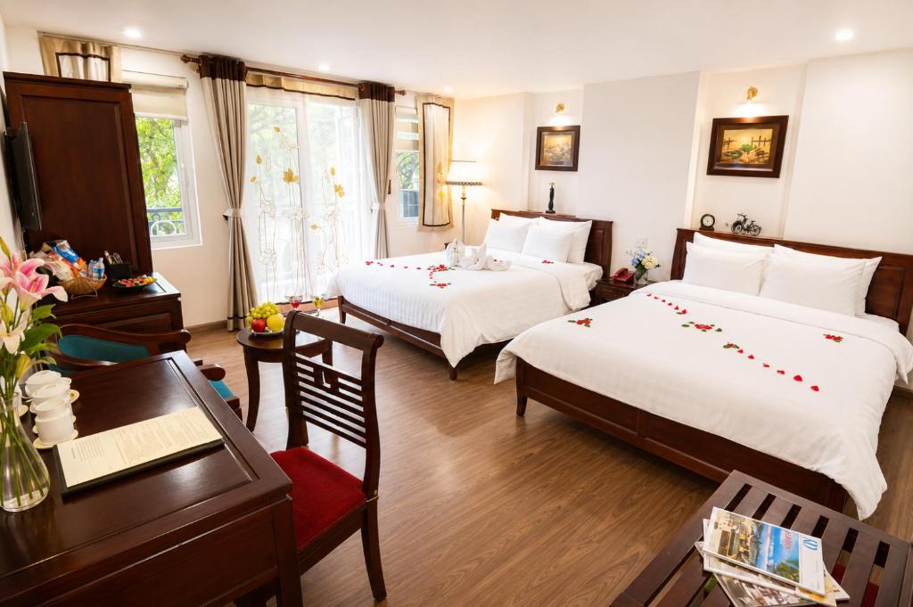 a hotel room with two beds and a table and a desk at Hanoi Luxury Hotel - Old Quarter in Hanoi