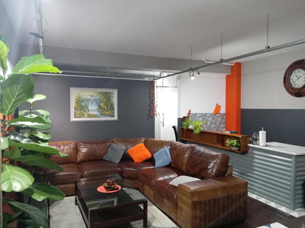 a living room with a brown leather couch at Warm & Luxury Stay at Maboneng with Kingbed HugeTV WiFi in Johannesburg