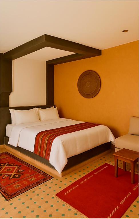 a bedroom with a large bed and a red rug at HOTEL RESTAURANT LA KaSBAH in Tinerhir
