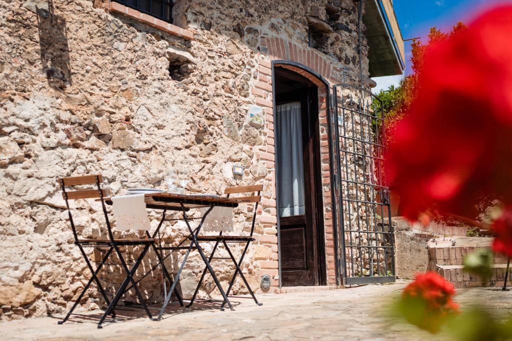two chairs and a table in front of a stone building at Tenuta La Selva Casa Pendio in Casal Velino