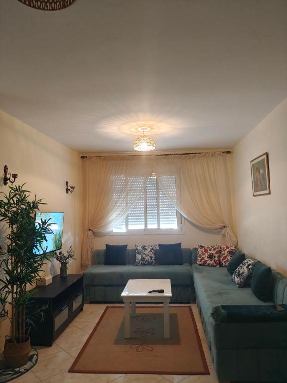 a living room with a blue couch and a table at Slow Life Bouznika in Bouznika