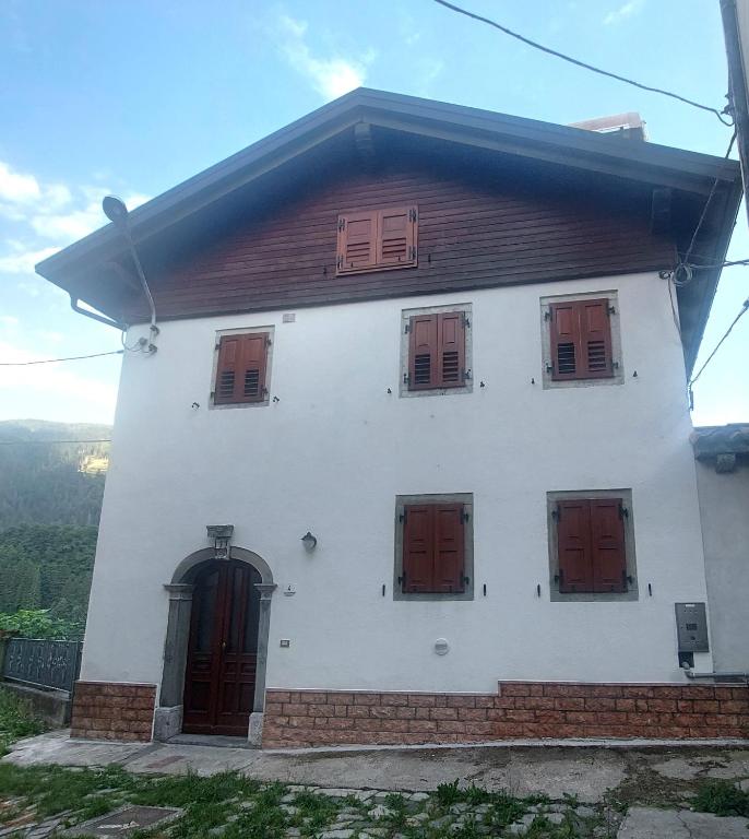 a white house with red doors and windows at Villa Mezzo in Paularo