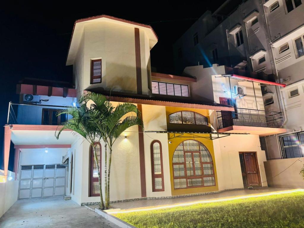 a house with a palm tree in front of it at Majestic Villa, 5 Bedroom AC in Mysore in Mysore