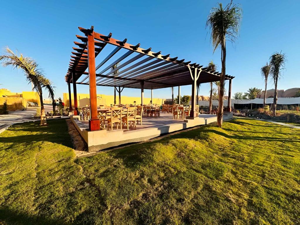a pavilion with tables and chairs on a grass field at Azad Siwa Hotel in Siwa