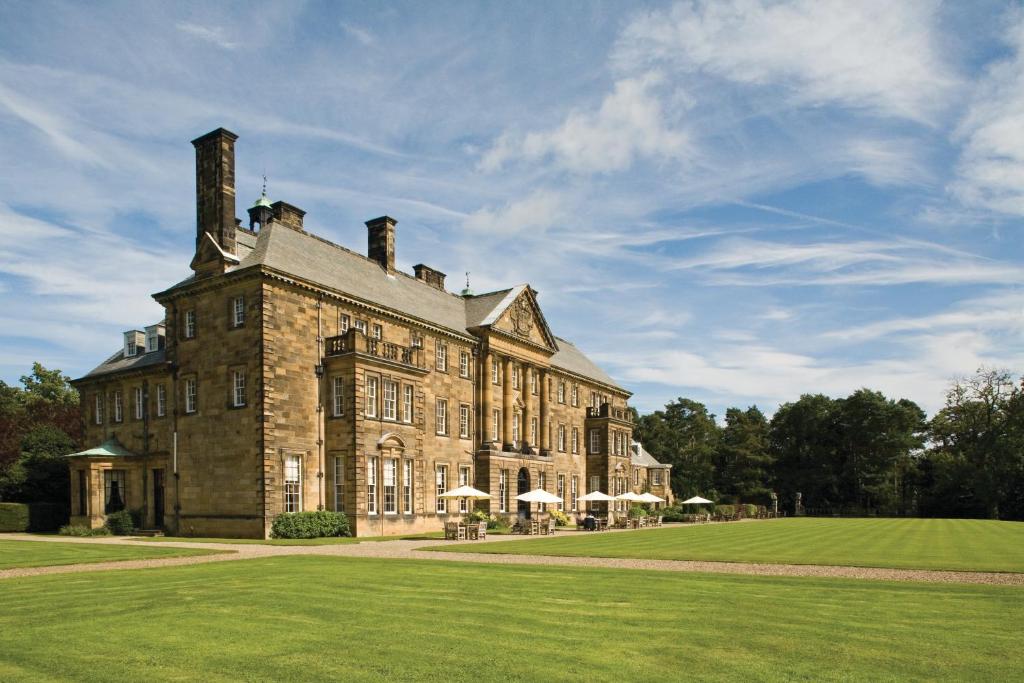 a large brick building with a grass field in front at Crathorne Hall in Yarm